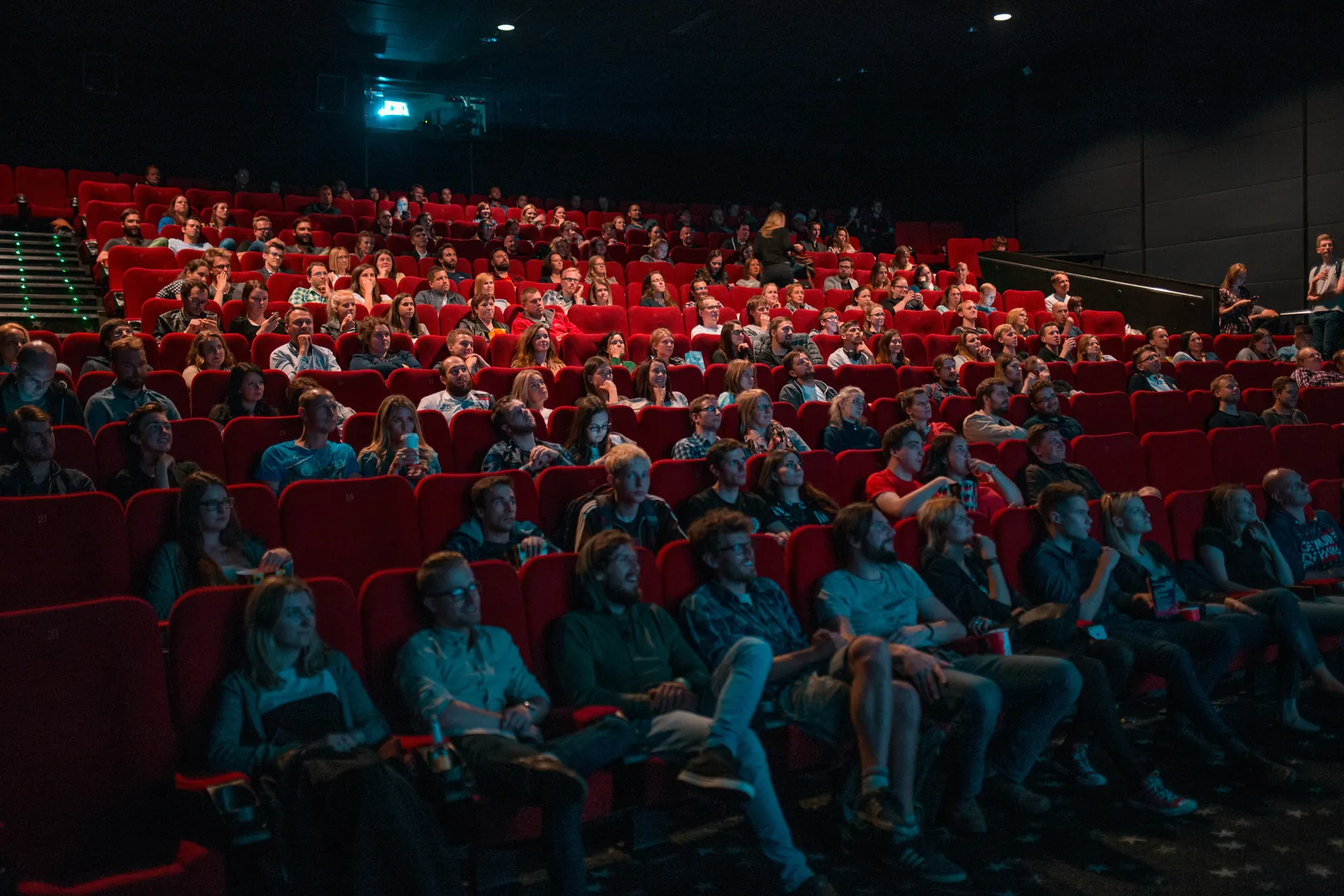 Public assis dans une salle de cinéma aux fauteuils rouges, pendant une séance.